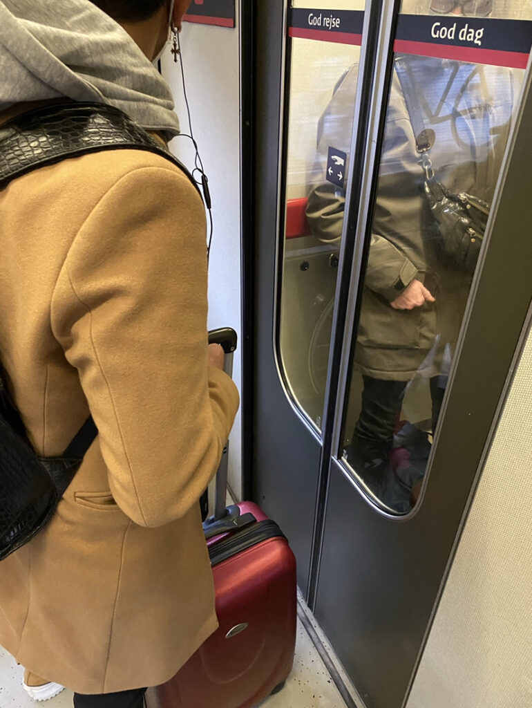 Two passengers standing near the door of a train in Copenhagen, but it remains closed due to some clever engineering