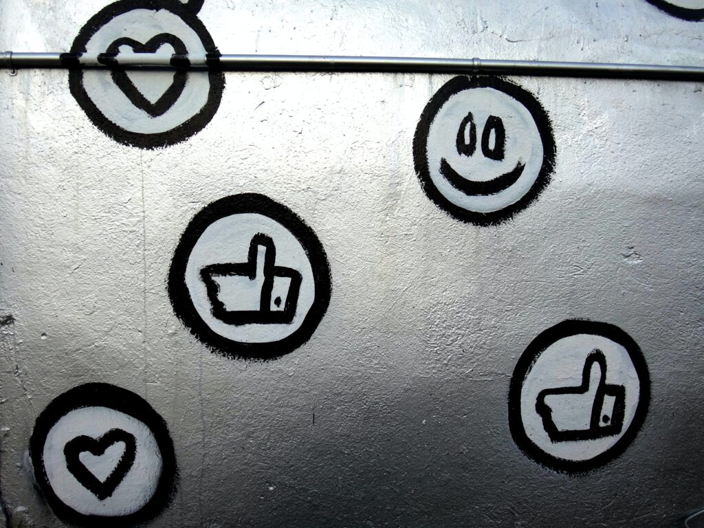 This is a silver wall, with graffiti of the Facebook reactions — a like, a heart, and a smiley face — drawn on it.