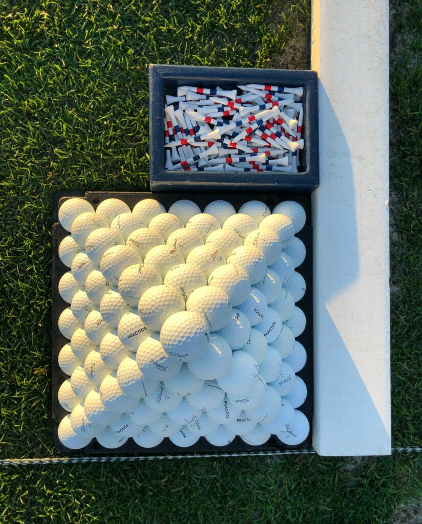 This is a photo of white golf balls and red, white, and blue golf tees on a driving range.