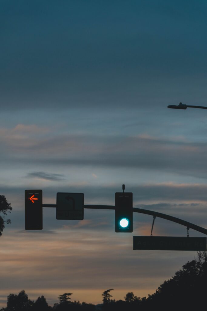 a photo of a green stoplight next to a red left turn arrow at dusk