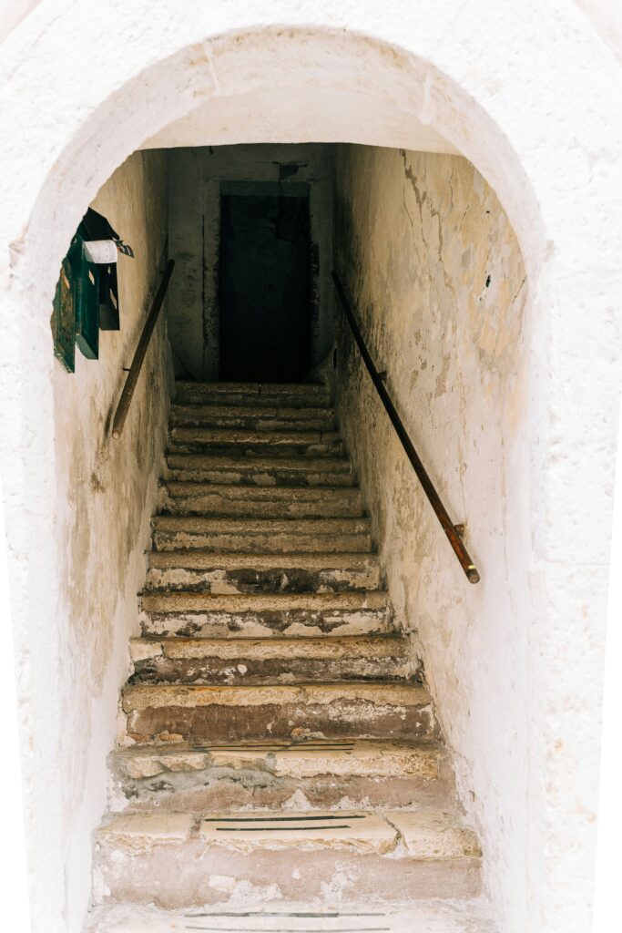 A concrete staircase, with a wooden railing on the right and brown spots on the stairs and walls.