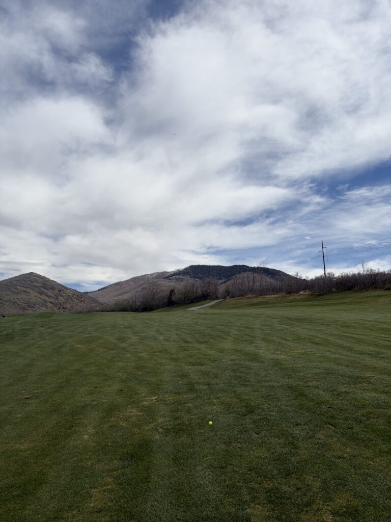 A white flag is visible in the distance, as are the mountains of Park City, as I stand over a yellow ball in the fairway.