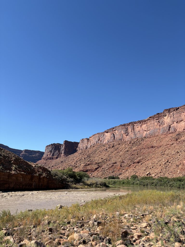 A photo of the muddy Colorado River, running beneath the red rocks near Moab, Utah.